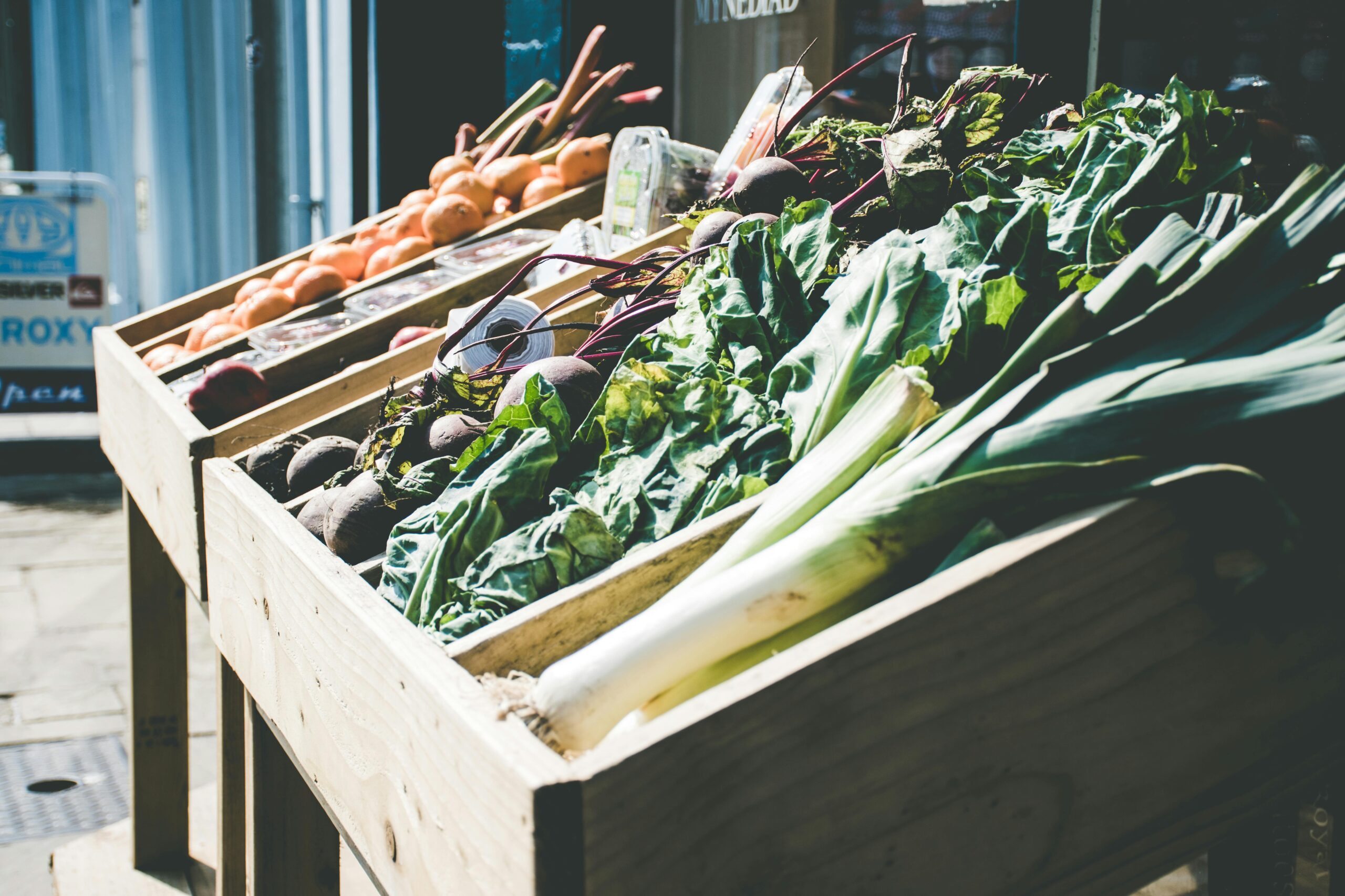 An array of fresh vegetables at an outdoor market stall, showcasing green leafy produce.