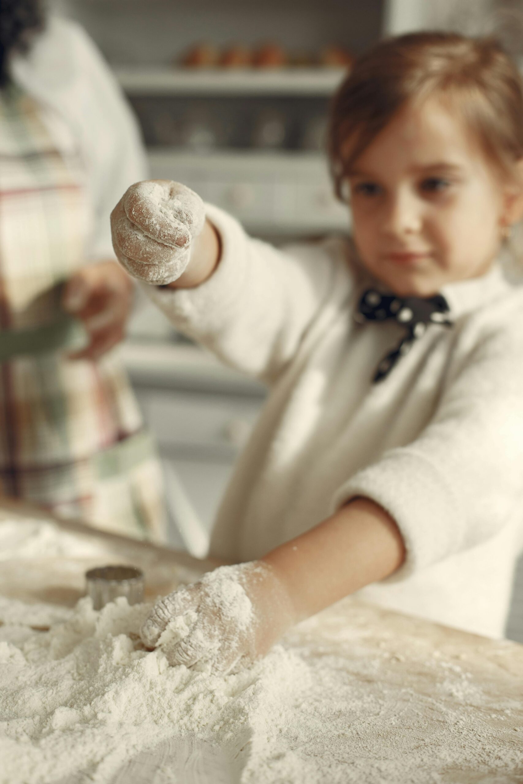 Young girl playing with flour while baking in a cozy home kitchen.